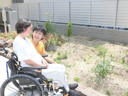 車椅子の女性と介護者の笑顔の写真